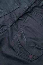 Close-up of a black denim pocket with detailed stitching and a small red logo.