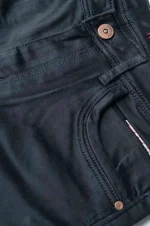 Close-up of a black denim fabric with a button and stitched seams.