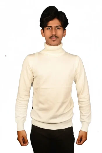A person stands confidently wearing a cream-colored turtleneck sweater and black pants against a plain white background.