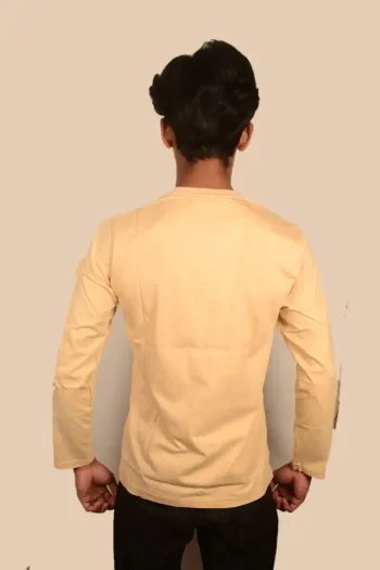 A person stands with their back to the camera, wearing a light beige long-sleeve shirt and dark jeans against a neutral background.